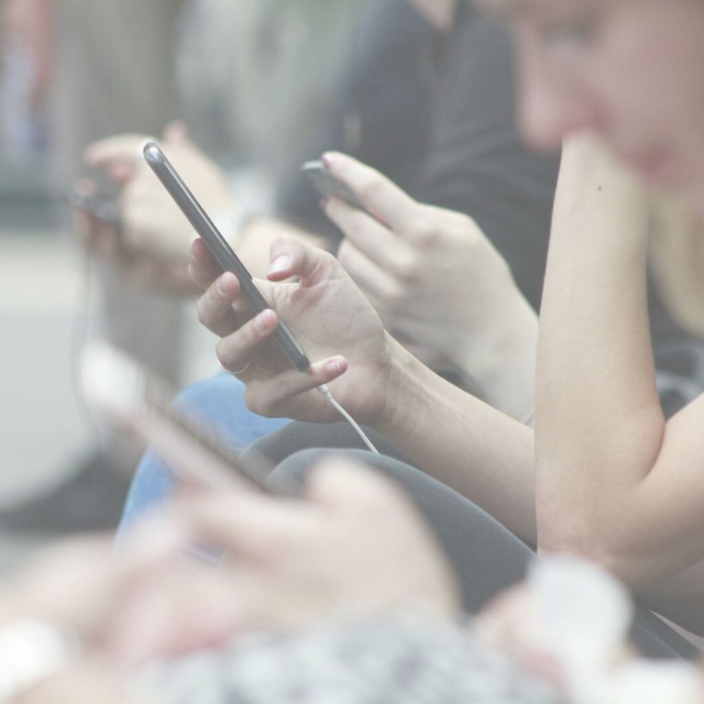 Jugendliche mit Smartphones in der Hand sitzen hintereinander