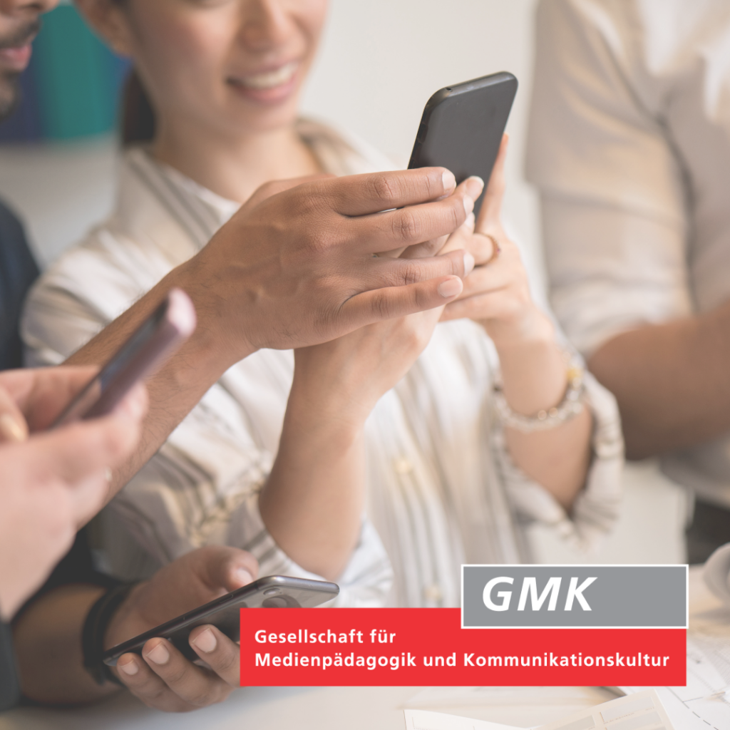 mehrere Personen schauen auf ihre Smartphones und interagieren dabei miteinander; rechts unten Logo der GMK