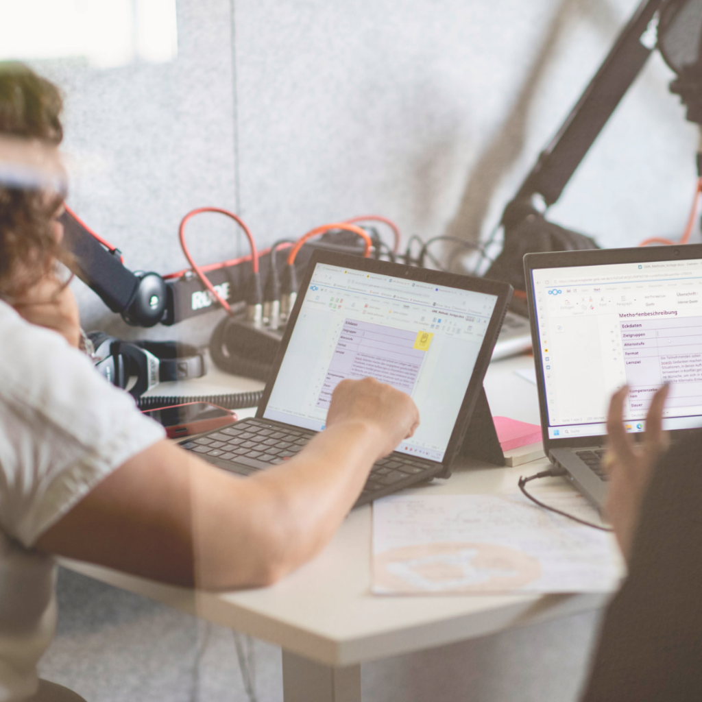 Zu sehen ist eine Ausschnitt aus einem Podcaststudio, in dem zwei Personen vor zwei geöffneten Laptops sitzen und an Methodenskizzen arbeiten.